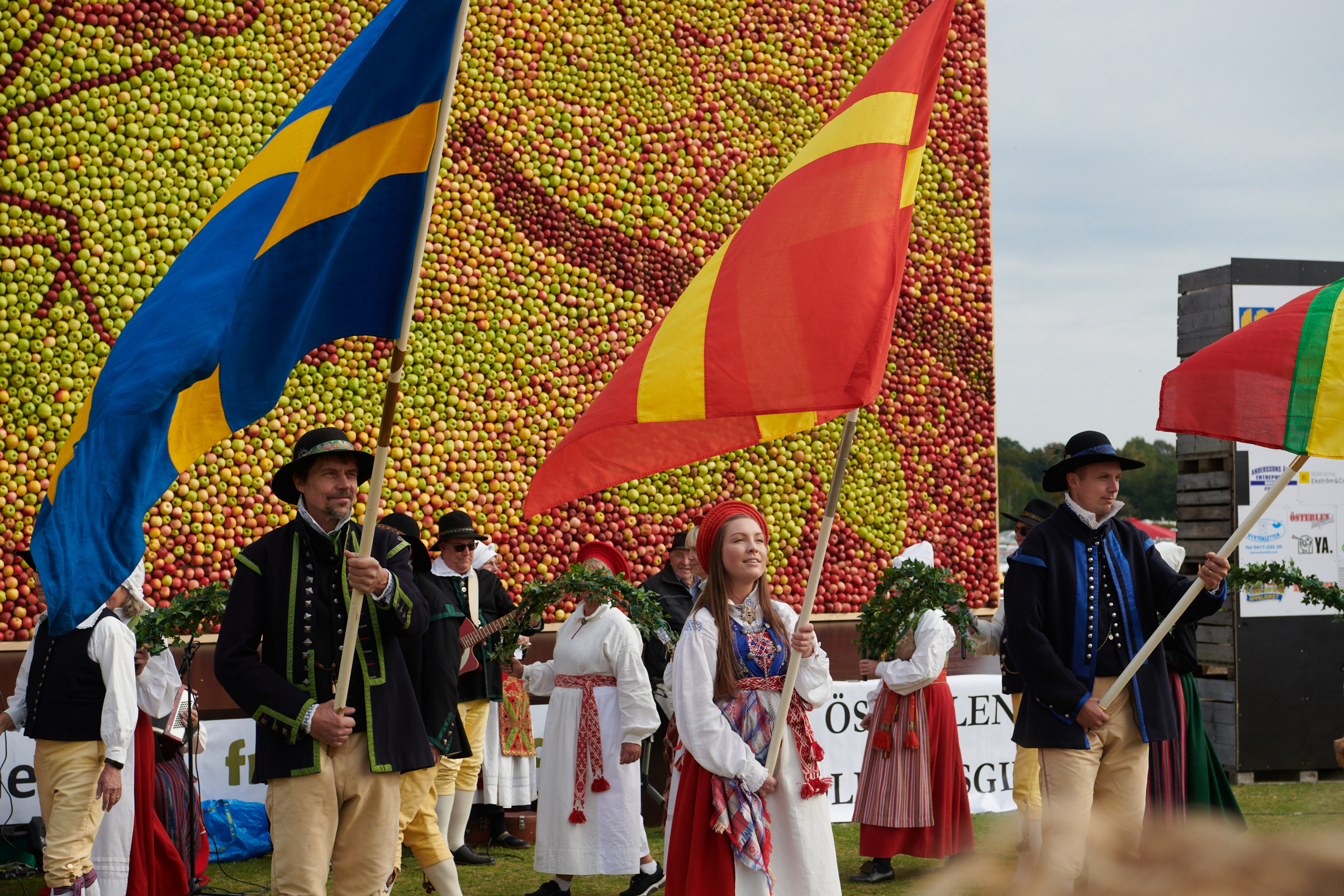 Folkdans och flaggor med äppeltavlan i bakgrunden